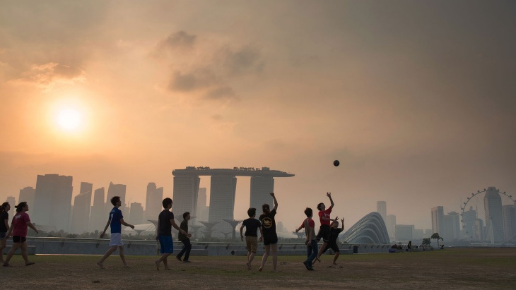 黃昏時(shí)分，一群男孩在濱海堤壩 (Marina Barrage) 上踢足球，遠(yuǎn)處是濱海灣的朦朧輪廓